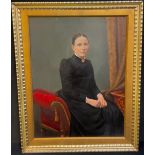 A Victorian overpainted portrait, of a lady seated o a red sofa, wearing a long black dress, 57cm