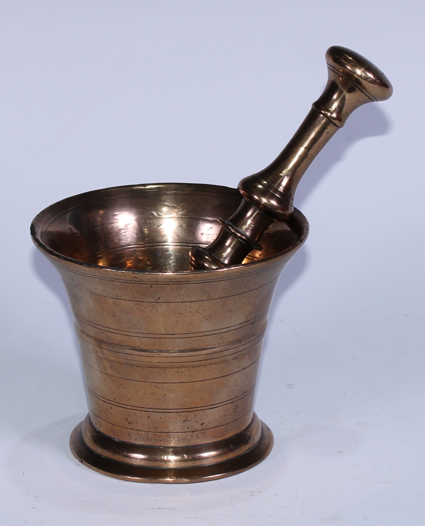 A bronze pestle and mortar, the flared cylindrical mortar ring-incised, 10.5cm high, 12.5cm