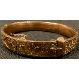 An Edwardian 9ct rose gold hinged bangle as a buckled belt, the front chased and engraved with