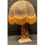 An Indonesian style carved openwork table lamp as a dragon, fringed wicker work shade, 57cm overall