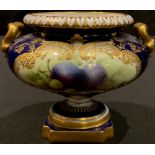 An early 20th century Royal Worcester gilded two handled pedestal urn, painted panel of fruit on