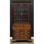 A George III Revival oak bureau bookcase, moulded cornice with dentil capital above a pair of glazed