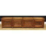 An early to mid-20th century oak low storage bench, hinged covers above panel doors, turned feet,