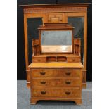 An Arts & Crafts period walnut accented two piece bedroom suite, comprising a triple-door wardobe