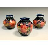 A pair of Moorcroft Pomegranate pattern ovoid vases, tube lined with fruit, blue ground, 8.5cm high,