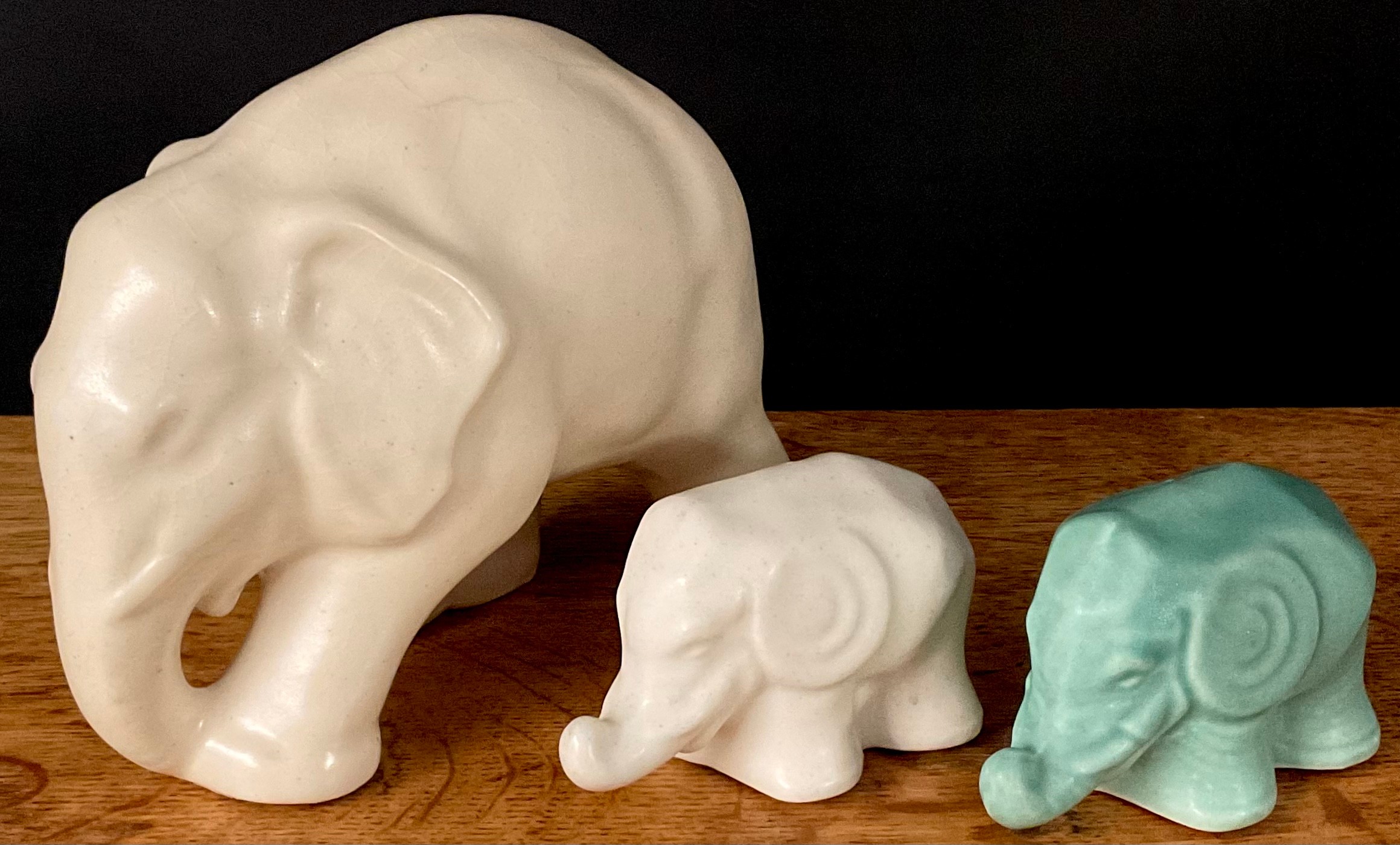 A Lovatts Langley elephant, in cream, 14cm high; two other stylised elephants, in cream and green,