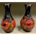 A pair of Moorcroft Pomegranate pattern bottle vases, tube lined with fruit, blue ground, 28.5cm