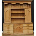A substantial farmhouse pine dresser, outswept cornice above three plate racks and a pair of panel