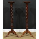 A pair of mahogany torchères, each with a dished circular top, lotus grasped wrythen column,