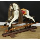 A 20th century rocking horse on a later replacement safety stand, the carved and later over-