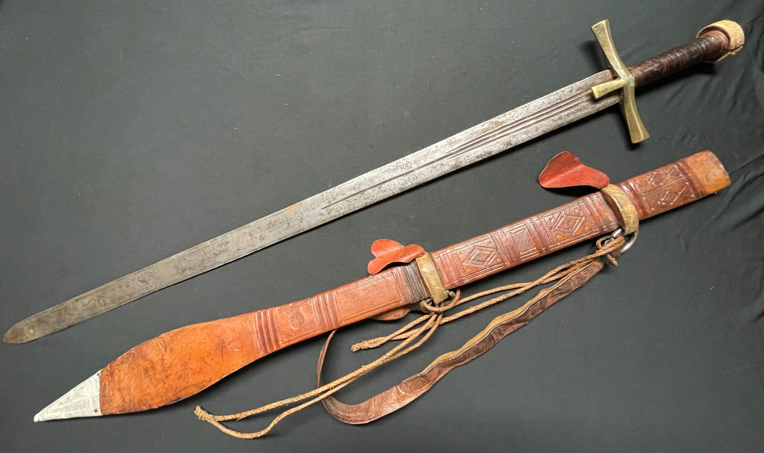 A Sudanese Kaskara sword with double edged blade 855mm in length. Brass crossguard. Leather bound