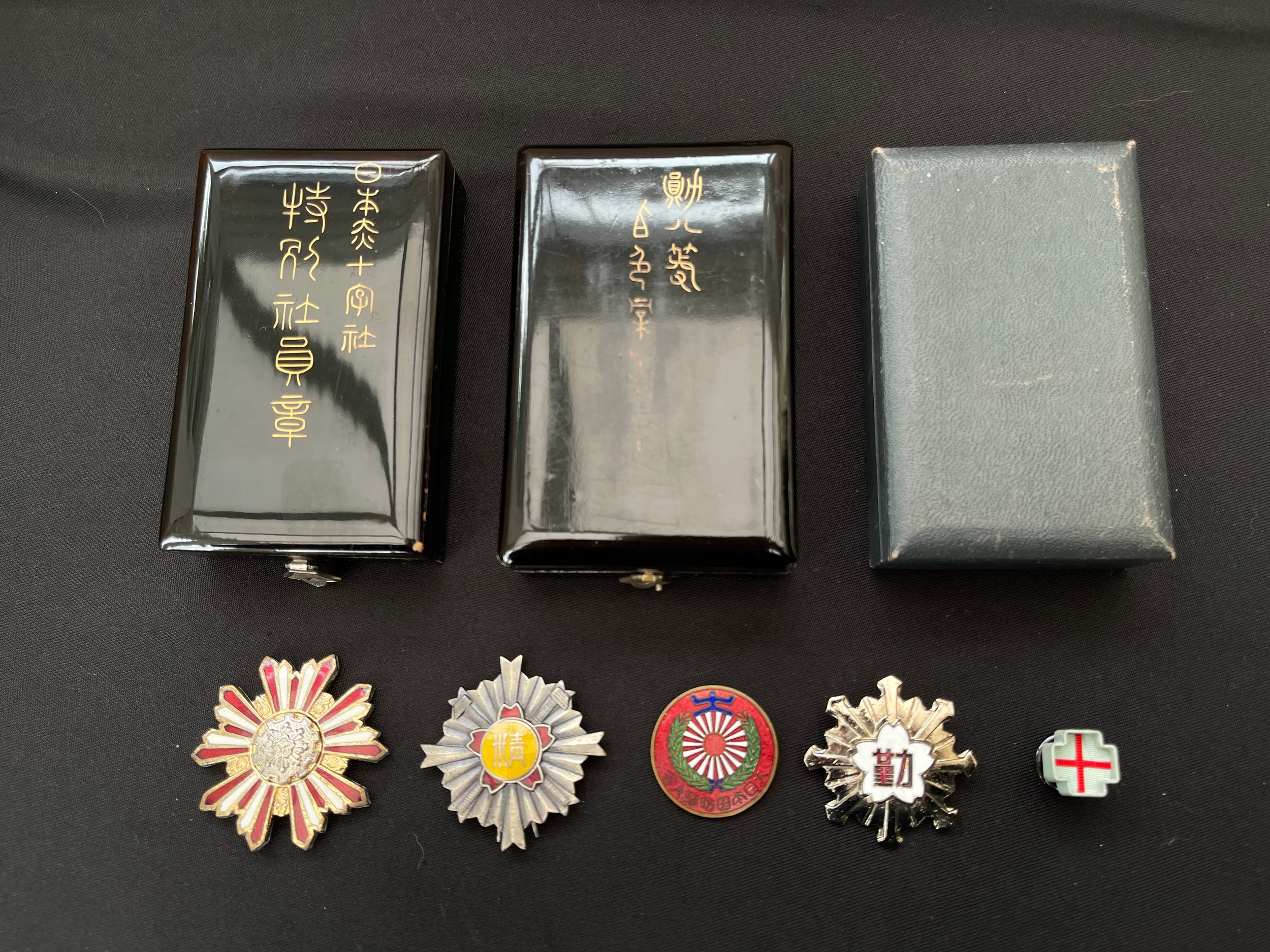 Japanese Patriotic enamel badges and three empty medal boxes.