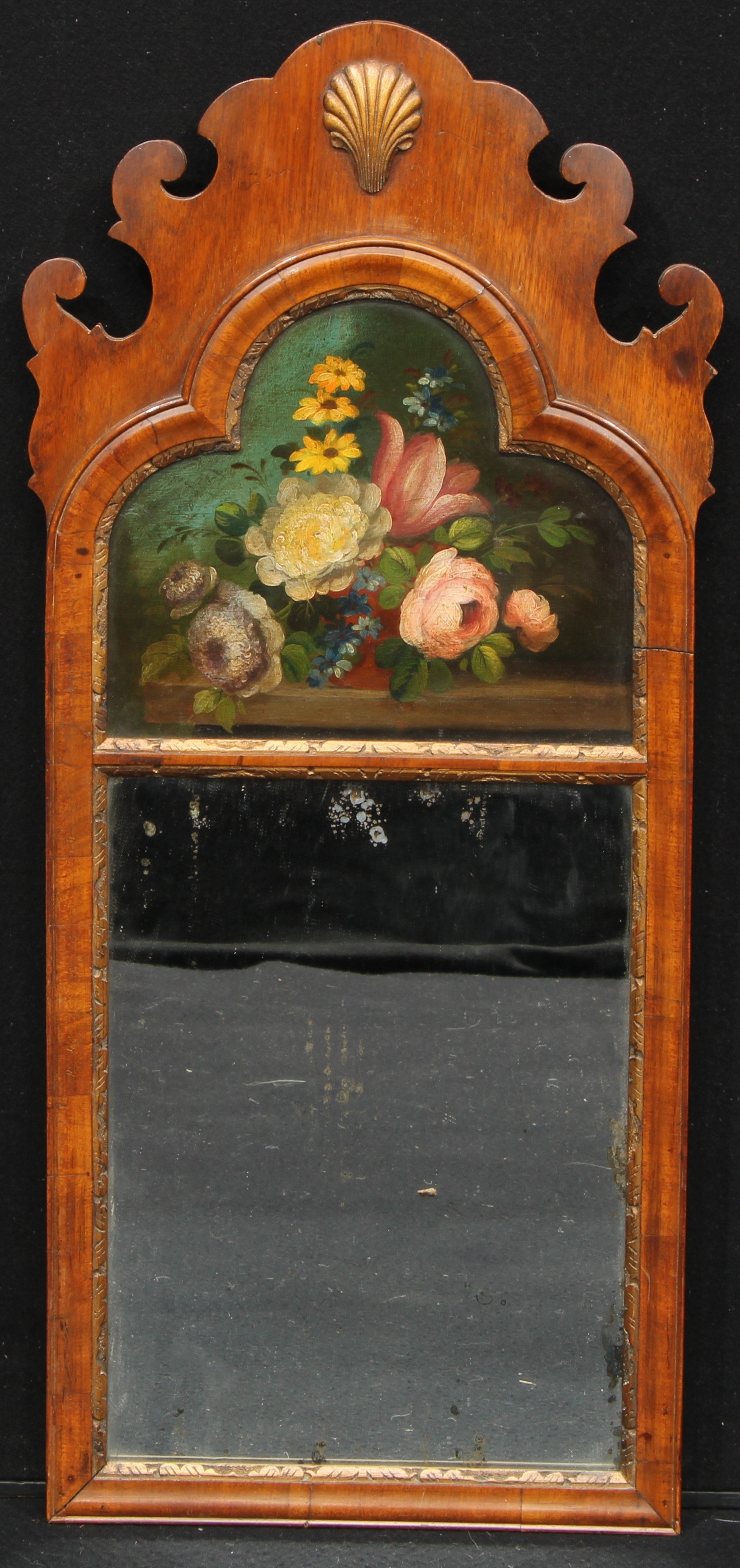 A George II Revival walnut and parcel-gilt Vauxhall looking glass, shaped cresting centred by a