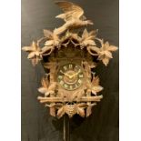 A Black Forest cuckoo clock, 17cm dial applied with Roman numerals, the case carved and applied with