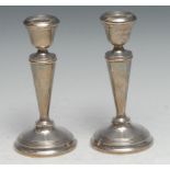 A pair of George V silver candlesticks, campana sconces, tapered pillars, domed bases with reeded