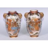 A pair of Japanese satsuma panelled ovoid vases, decorated with figures and landscapes, scroll lug