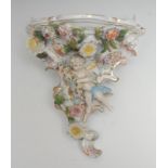 A German wall bracket, encrusted with flowers and cherub with garland, in pastel tones, picked out
