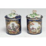 A pair of Derby cylindrical pots and covers, decorated with shaped gilt cartouches with figures in a