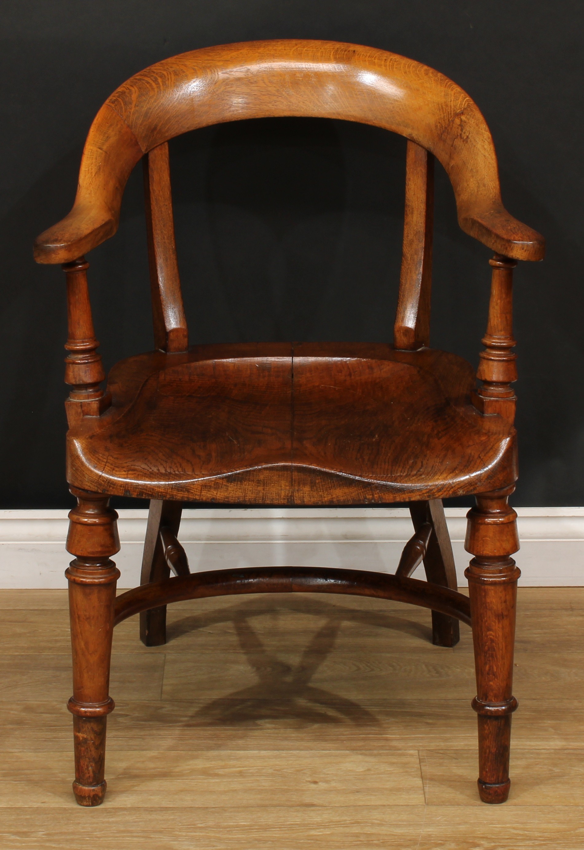 A Victorian oak desk chair, curved cresting rail, turned arm posts, saddle seat, turned forelegs,