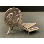 A miniature continental silver tilt top table, embossed circular top, tripod base, indistinctly