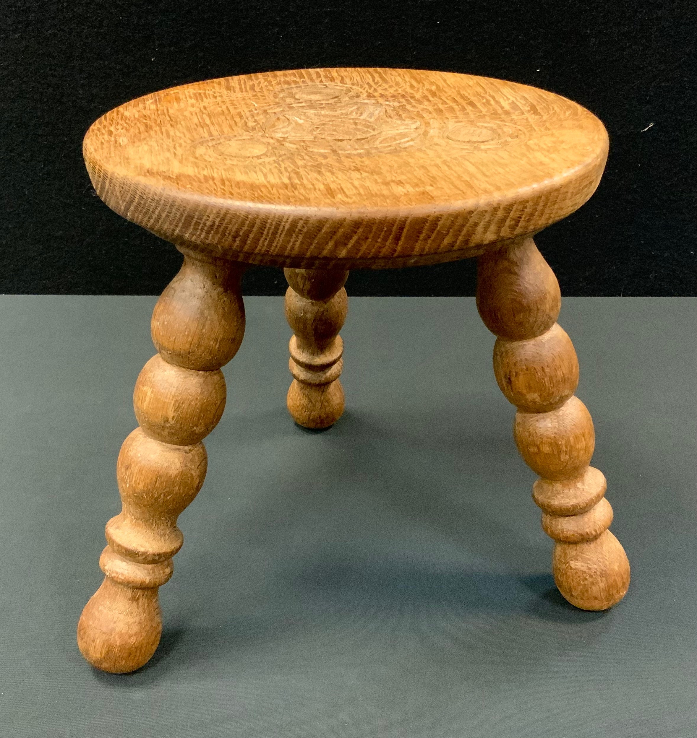 A Hunstone hand carved light oak stool, carved seat, turned tripod legs, 26cm high, 25cm diameter