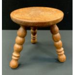 A Hunstone hand carved light oak stool, carved seat, turned tripod legs, 26cm high, 25cm diameter