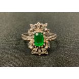 An Art Deco diamond and emerald dress ring, central rectangular cushion cut emerald (treated) within