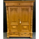A Victorian pine double wardrobe, outswept cornice above a pair of carved panel doors enclosing