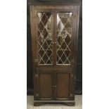 A 20th century oak corner cabinet, a pair of astragal cupboard doors enclosing shelves above a