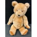 A mid 20th century gold plush teddy bear, hump back body, plastic eyes, vertical stitched nose, 46cm