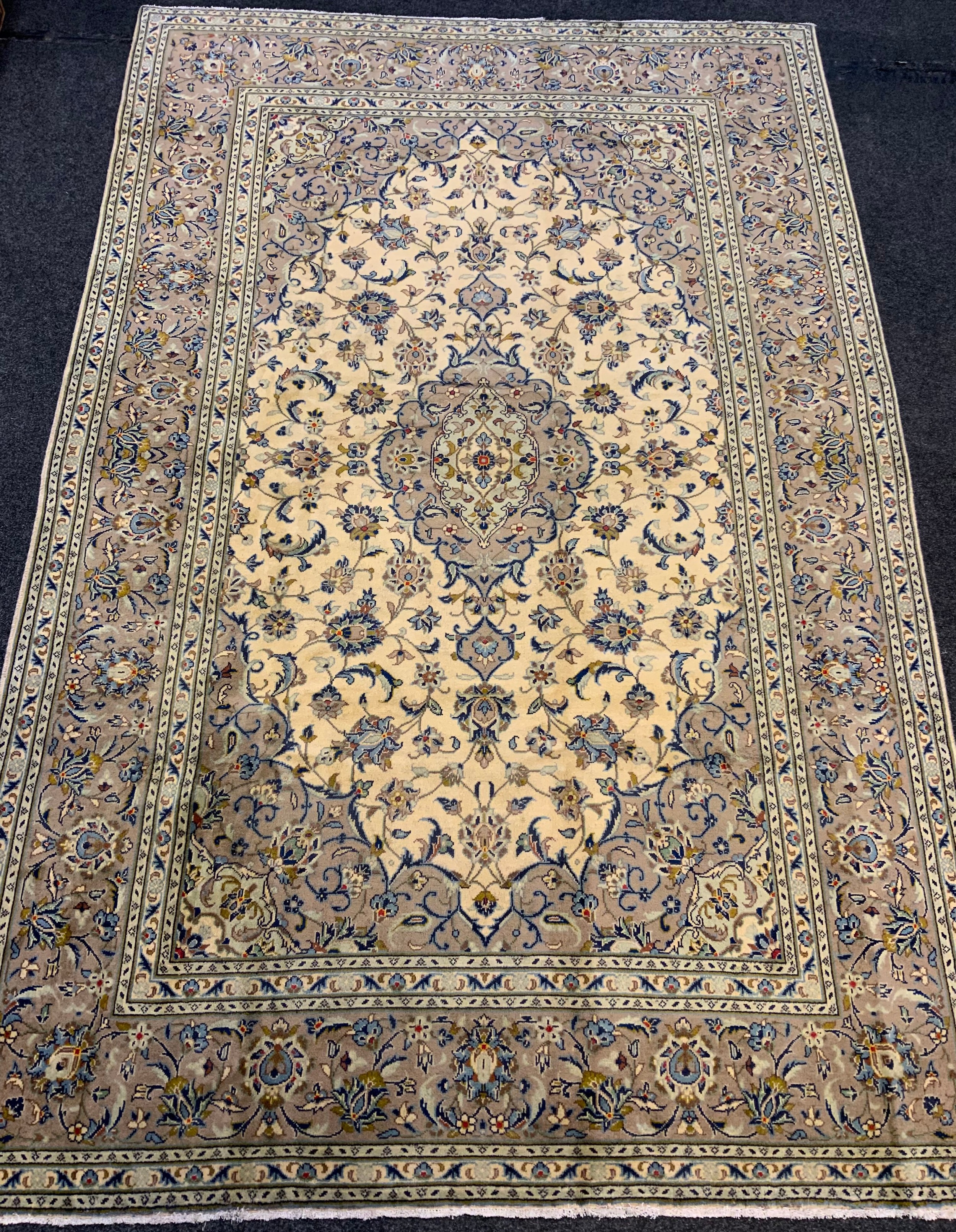 A fine Kashan rug / carpet, woven in muted tones of grey, blue, and cream, 310cm x 205cm.