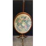 A late Victorian mahogany pole screen, the glazed oval screen with an embroidered floral panel,