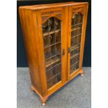 An early 20th century walnut display cabinet, the two doors with slightly bowed astragal glazed