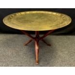 A large, Persian style, brass tray-top table on a collapsible carved wooden tripod base, mid 20th