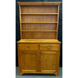 A narrow pine dresser, three tiers of shelving above pair of short drawers and pair of cupboard