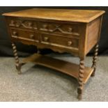 A mid 20th century oak low boy / canteen, over sailing top above two pairs of short drawers,