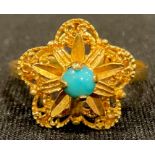 An 18ct gold star shaped filigree ring, set with a single polished turquoise stone, size O, marked