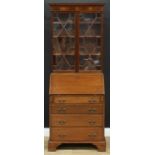 An early 20th century mahogany bureau bookcase, of narrow proportions, outswept cornice above a pair
