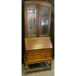 An early 20th century oak bureau bookcase, arched-top with glazed doors enclosing three tiers of