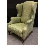 A Queen Anne style wingback armchair, cabriole legs, green upholstery, c.1920