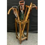 An early 20th century oak stick stand; shooting sticks; rustic walking sticks; etc