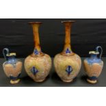 A pair of Doulton Lambeth ewer, incised with swirls, in gilt, mottled blue necks and handles, 20cm