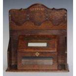 A late Victorian oak country house letter box, shaped cresting above four pigeon holes and a