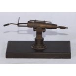 An early 20th century brass articulated desk model, of a harpoon gun, rectangular base, 12.5cm wide