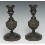 A pair of Regency brown patinated bronze candlesticks, campana sconces, each with fluted knop