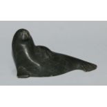 An Inuit greenstone carving, of a seal, 11cm wide, inscribed BA**, 5N40519, ink manuscript label and