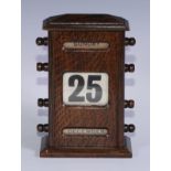An early 20th century oak perpetual desk calendar, sarcophagus cresting above glazed day, date and