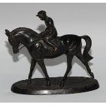 A Continental dark patinated equestrian desk sculpture, cast as a horse and jockey, oval base,