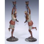A pair of cold painted blackamoor candlesticks, cast in the Orientalist taste as turbaned figures,