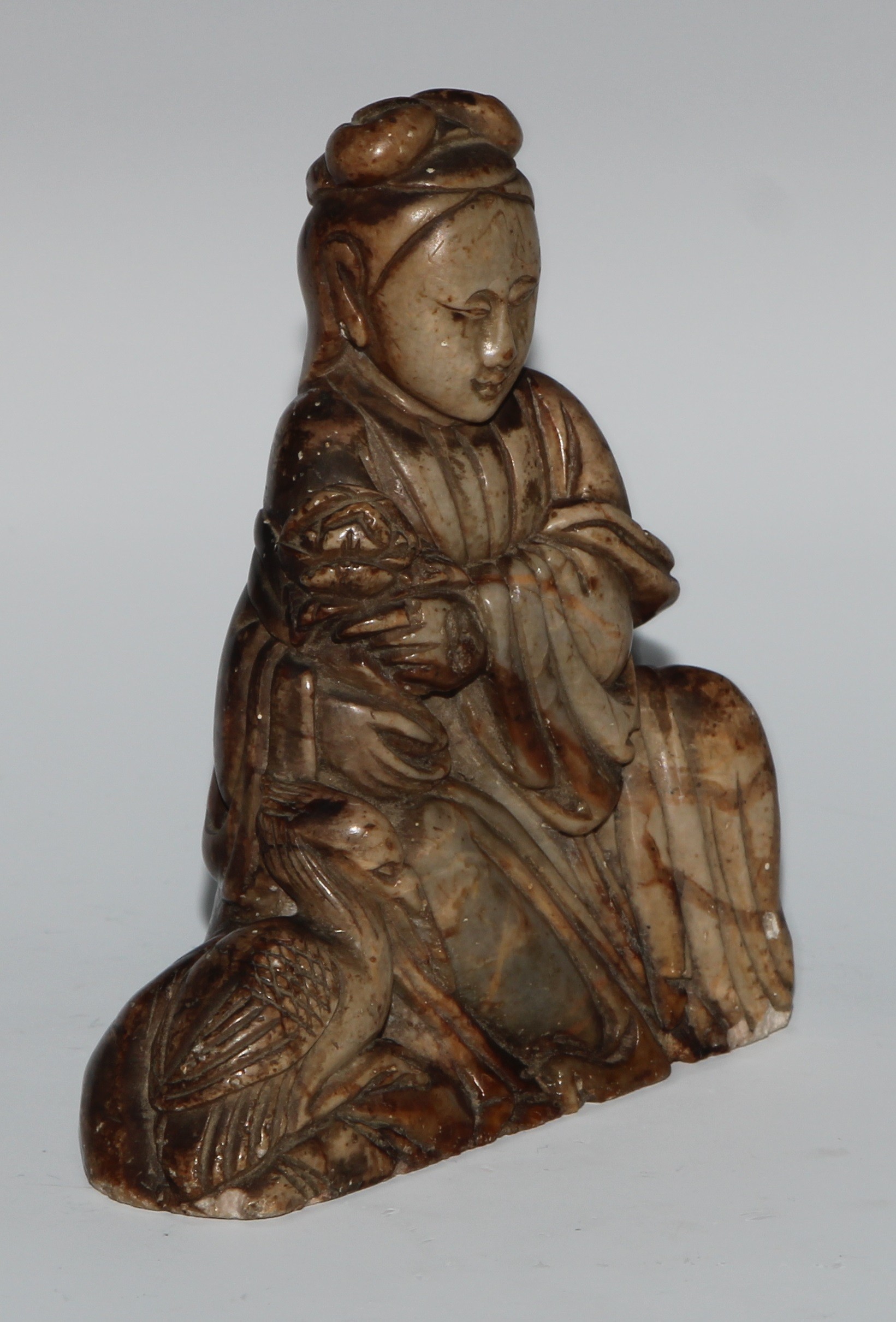 A Chinese soapstone figure, carved as guanyin, seated, serene, holding a lotus, a bird at her - Image 2 of 4